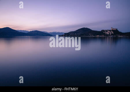 Arona, Lago Maggiore, Italy.A malerischen Blick von der Uferpromenade in Richtung Stadt von Angera, mit seiner Burg auf dem gegenüberliegenden Ufer Stockfoto