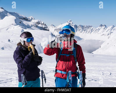 Zwei Skifahrer einen Snack essen eine Banane und das Trinken aus einer Wasserflasche zum Skifahren auf Pisten in die Französischen Alpen. Flaine Rhone-Alpes Frankreich EU Stockfoto