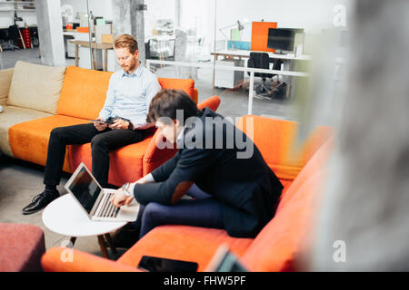 Industrie-Kollegen entspannend auf Sofa in Pause Stockfoto