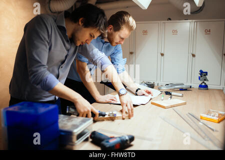 Zwei Designer arbeiten zusammen in der Werkstatt mit Präzisionswerkzeugen Stockfoto