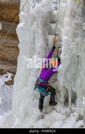 Frau Eiskletterer aufsteigend einen gefrorenen Wasserfall in dargestellter Felsen-Staatsangehöriger Lakeshore, obere Halbinsel, Michigan, USA Stockfoto