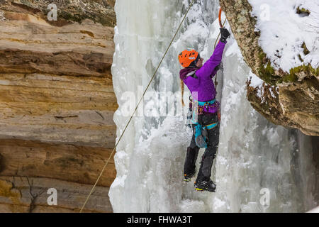 Frau Eiskletterer aufsteigend einen gefrorenen Wasserfall in dargestellter Felsen-Staatsangehöriger Lakeshore, obere Halbinsel, Michigan, USA Stockfoto