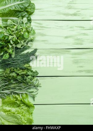 Grüne Kräuter auf dem grünen hölzernen Hintergrund. Stockfoto