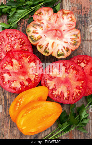 Verschiedene bunte saftige Reife Heirloom Tomatoes auf rustikalen Holz Hintergrund Stockfoto