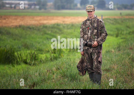 Jäger in Camouflage mit Schrotflinte Holding Enten in der hand. Mann Jagd Enten Stockfoto