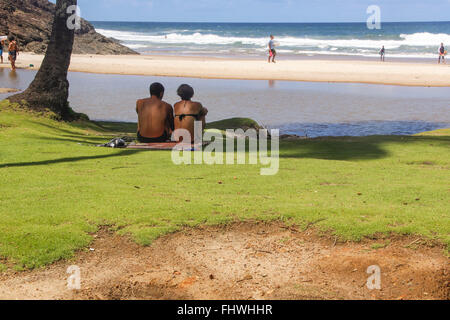 Paar, sitzen im Schatten eines Baumes auf der Wiese am Rande des Praia da Costa Stockfoto