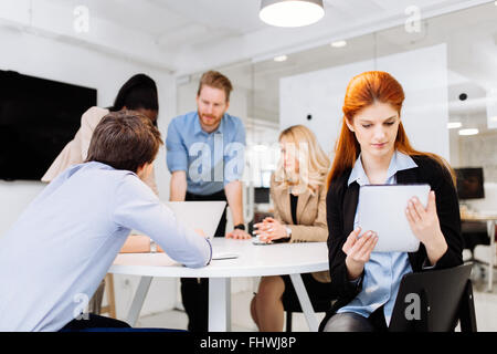 Geschäftskollegen mit Technologie griffbereit am Schreibtisch sitzen Stockfoto