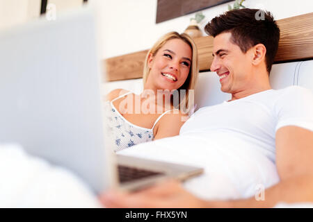 Schönes Paar mit Laptop im Bett während wirklich glücklich zu sein Stockfoto