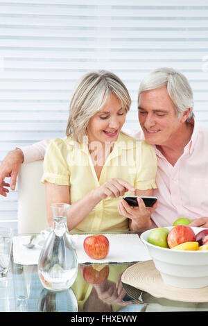 Älteres Paar mit Smartphone am Frühstückstisch Stockfoto