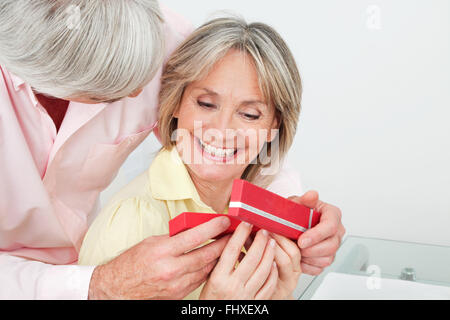 Glücklich lächelnde senior Frau Geschenk von ihrem Ehemann empfangen Stockfoto