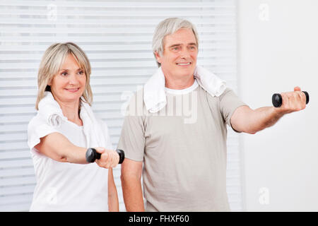 Zwei glückliche aktive Senioren tun Fitness-Training im Fitnessstudio mit Hanteln Stockfoto