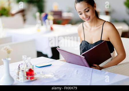 Schöne Frau-Menü im Restaurant bestellen und entscheiden, was zu essen Stockfoto