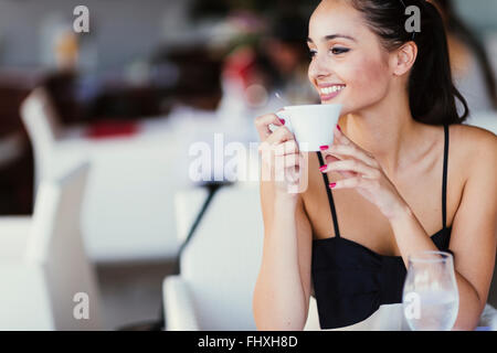 Schöne Frau trinkt Tee im Restaurant während des Wartens auf ihre Mahlzeit Stockfoto