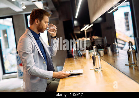 Geschäftsmann, Trinkwasser und Morgenzeitung lesen Stockfoto