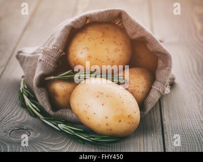 Babykartoffeln in Sack Tasche mit Rosmarin auf Holztisch Stockfoto