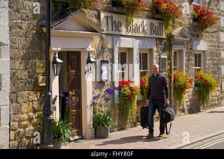 Mann zu Fuß mit Fällen. Black Bull Pub, Corbridge, Northumberland, England, Vereinigtes Königreich, Europa. Stockfoto