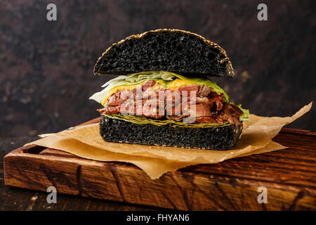 Schneiden Sie in halbe Roastbeef Burger mit in Scheiben geschnittenen Pastrami auf dunklem Hintergrund Stockfoto