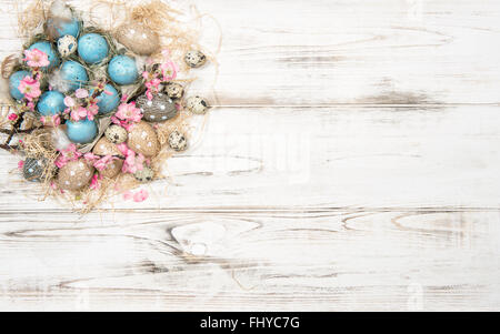 Oster-Deko mit blauen Eiern und rosa Blumen auf hellem Holz Hintergrund Stockfoto