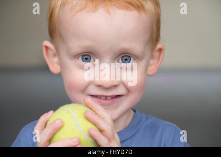 Roten Haaren, blauen Augen junge schließen sich, Lächeln und ein Tennis-Ball-Schuss halten Nahaufnahme Stockfoto
