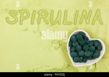 Spirulina. Grüne Nahrungsergänzung. Wort-Spirulina in grünem Grund Pulver, Ansicht von oben geschrieben. Gesunde Lebensweise. Stockfoto