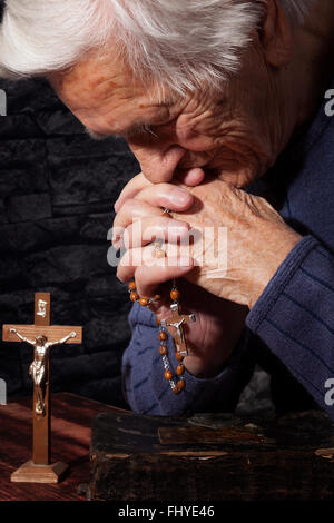 Großmutter zu beten. Alte faltige schöne Frau mit Rosenkranz beten. Glaube, spirituell und Religion. Stockfoto
