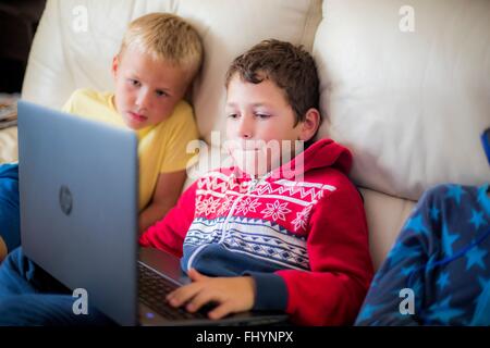 -MODELL VERÖFFENTLICHT. Zwei jungen mit einem Laptop auf dem Sofa sitzen. Stockfoto