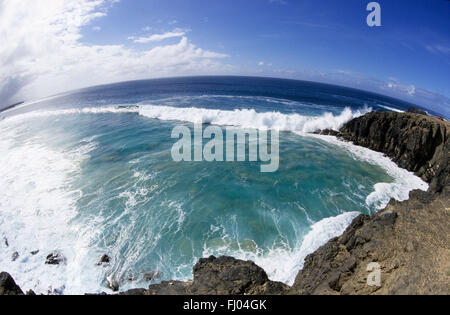 Fish eye Blick auf riesige Wellen Rollen in Klippen und Strand unter einem gewölbten blauen Himmel auf Fuerteventura, Kanarische Inseln Stockfoto