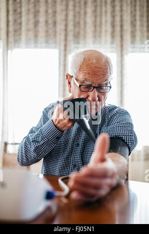 Senior woman kontrolliert seinen Blutdruck zu Hause Stockfoto