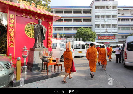 Buddhistische Mönche gehen vorbei an einem Schrein in Bangkok, Thailand Stockfoto