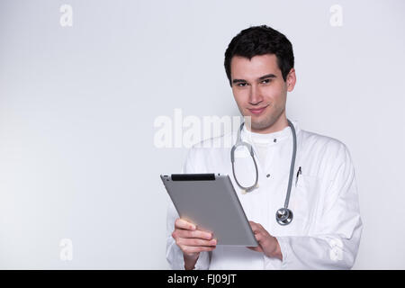 junger Arzt, Mann im weißen Kittel mit Stethoskop mit Tablet-pc arbeiten Stockfoto