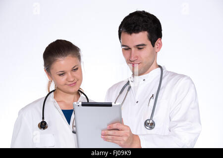 zwei junge Ärzte, männlich und weiblich in weißen Kitteln mit Stethoskop mit Tablet-pc arbeiten Stockfoto