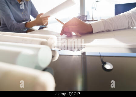 Team von zwei weiblichen Architekten, mit Bauplänen auf Schreibtisch am Schreibtisch im Büro sitzen. Ansicht von Hand mit Bleistift beschnitten. Stockfoto