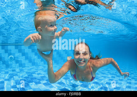 Kind-Schwimmunterricht - Baby junge mit Mutter unter Wasser im Pool mit klaren, blauen Wasser tauchen zu lernen.