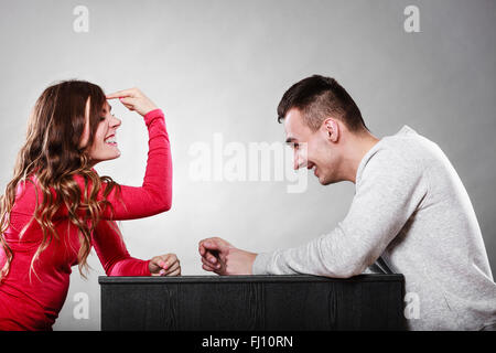 Frau mit Finger auf ihrem Kopf sitzt vor Mann gestikulieren. Bist du verrückt? Mädchen spöttischen Lachen Mann. Stockfoto