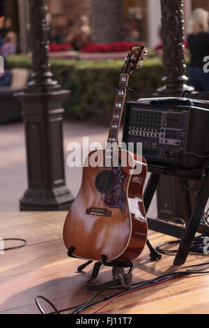 6-Saiter Akustik-Gitarre sitzt auf einem Ständer auf einer Freilichtbühne, bereit für eine live-Musik-Performance. Stockfoto