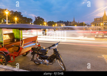 Ein Tuk Tuk ist vor Königspalast von Phnom Penh in Kambodscha Hauptstadt abgestellt. Der Verkehr wird mit Langzeitbelichtung, eingefangen. Stockfoto