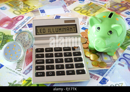 Taschenrechner mit den Worten LED Leuchtmittel, zwei LED-Lampen und ein grünes Sparschwein auf einem Hintergrund von Euro-Banknoten hergestellt und Stockfoto