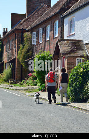 Ansicht der Rückseite des erwachsenen Mann und Frau Wandern mit Hund durch das attraktive Dorf Itchenor, Chichester Harbour, West Sussex, England, Großbritannien Stockfoto