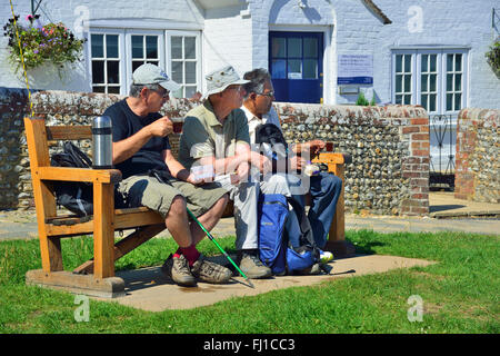 Drei männliche Wanderer ruhen auf einem Platz für eine Tasse Tee im Dorf Itschenor, Chichester Harbour, West Sussex, England, Großbritannien Stockfoto