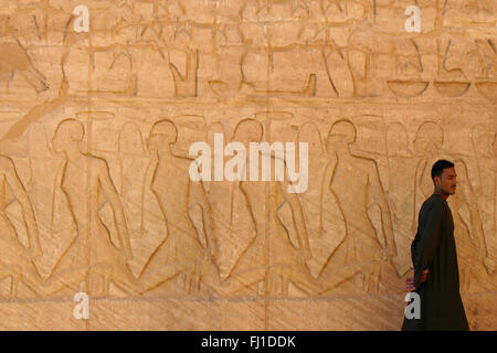 Ein Mann Spaziergänge entlang der Wand schnitzereien vor Abu Simbel Tempel, Ägypten Stockfoto