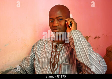 Portrait von Stattlichen kahlen schwarzen afrikanischen Mann aus Mali mit Handy in Djenné Stadt posing Stockfoto