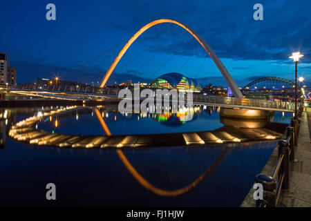 Nachtansicht der Gateshead Millennium Bridge spiegelt sich in den Fluss Tyne mit der Sage Gateshead & der Tyne Brücke im Hintergrund Stockfoto