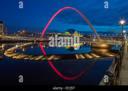 Nachtansicht der Gateshead Millennium Bridge spiegelt sich in den Fluss Tyne mit der Sage Gateshead & der Tyne Brücke im Hintergrund Stockfoto