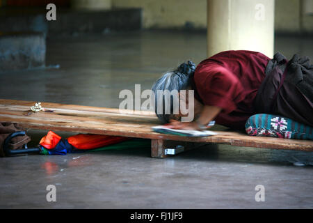 Alte buddhistische tibetische Flüchtlinge, die auf dem Boden Mac Leod Ganj Kloster beten, Indien Stockfoto