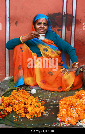 Frau, die Blumen und Tee trinken in Jaipur, Indien Stockfoto