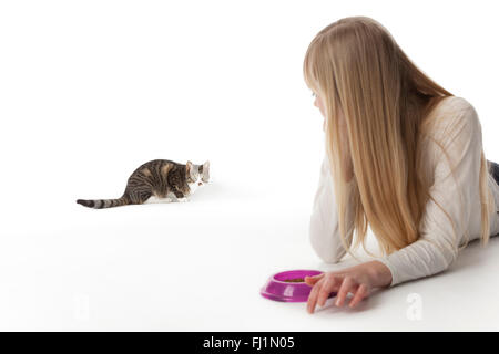 Teenager-Mädchen ruft ihre Katze auf weißem Hintergrund zu essen Stockfoto