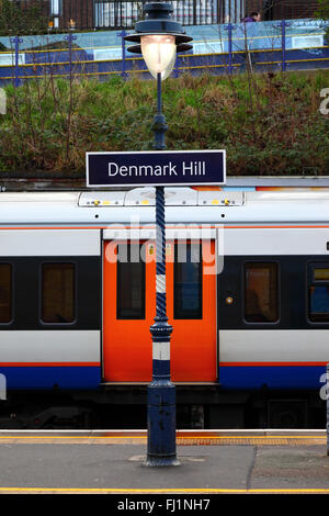 London Overground Train mit orangefarbenen Türen und Denmark Hill Railway Station Schild, Camberwell, London, England Stockfoto