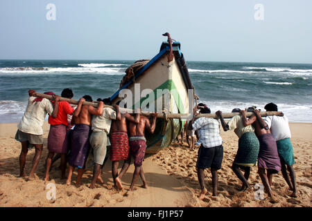 Fischer druck Boot Kanu auf das Meer vor dem Angeln am Strand von Puri, Orissa, Indien Stockfoto