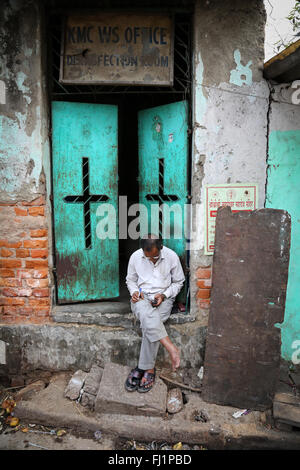 Mann lesen in einer Straße von Kolkata mit offenen grünen Tür hinter hiù Stockfoto