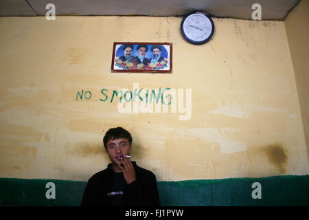 Kaschmir Mann rauchen im Restaurant in Leh, Indien, unter einem Rauchverbot Schrift an der Wand Stockfoto